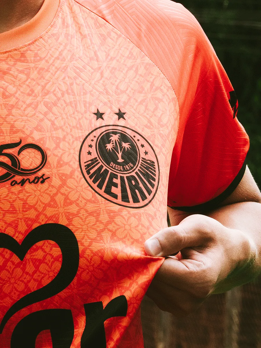 Detalhe do escudo na camisa laranja com textura em relevo