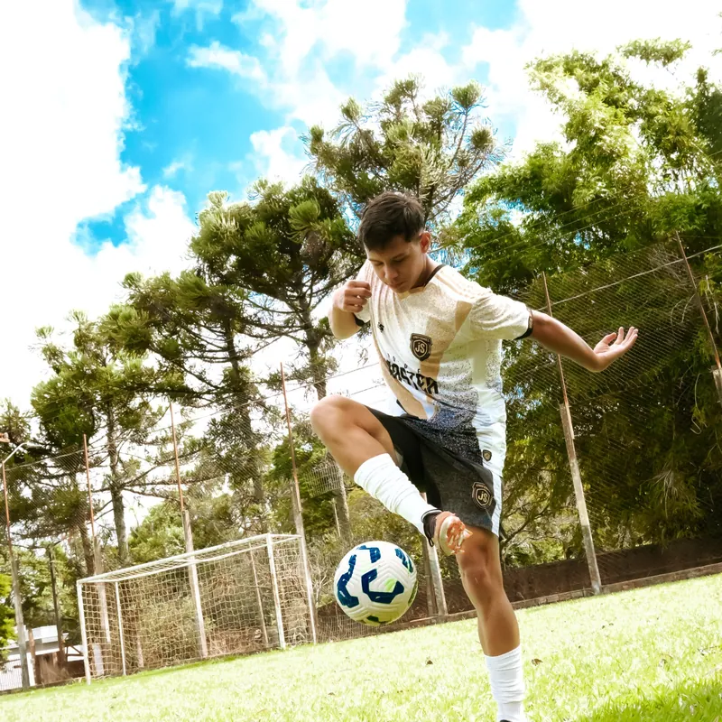 Atleta dominando a bola com uniforme branco e dourado