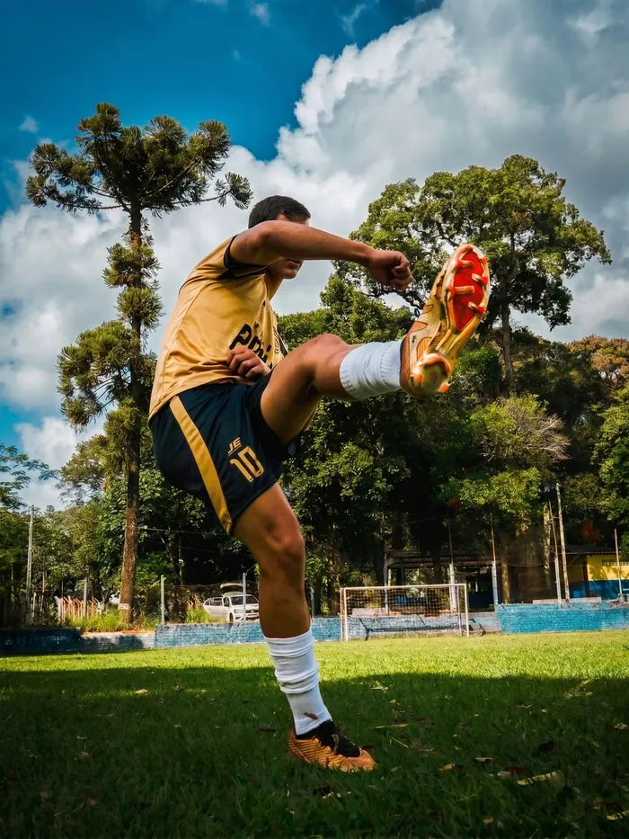 Atleta chutando com uniforme dourado